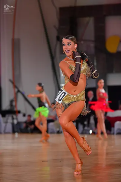 Dancesport competitor #70: Female dancer in foreground: gold/bronze sequin latin dress with fringe and long