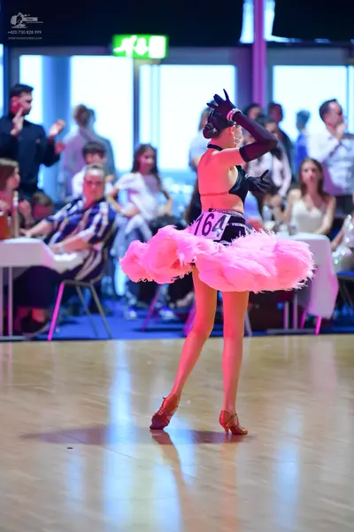 Dancesport competitor #164: Female dancer: black top, voluminous pink feathered skirt, long black gloves, an