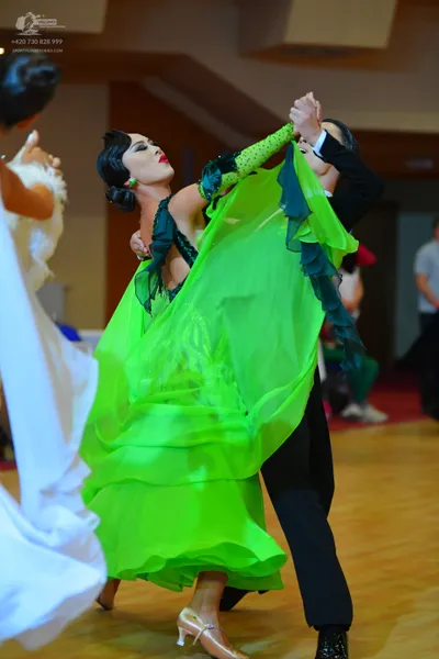 Dancesport competitor: Female dancer in foreground: lime green Latin dress with a flowing, layered skir