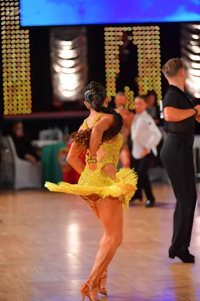 Dancesport competitor: Female dancer: yellow/gold sequined Latin dress with a cut-out back and short, f