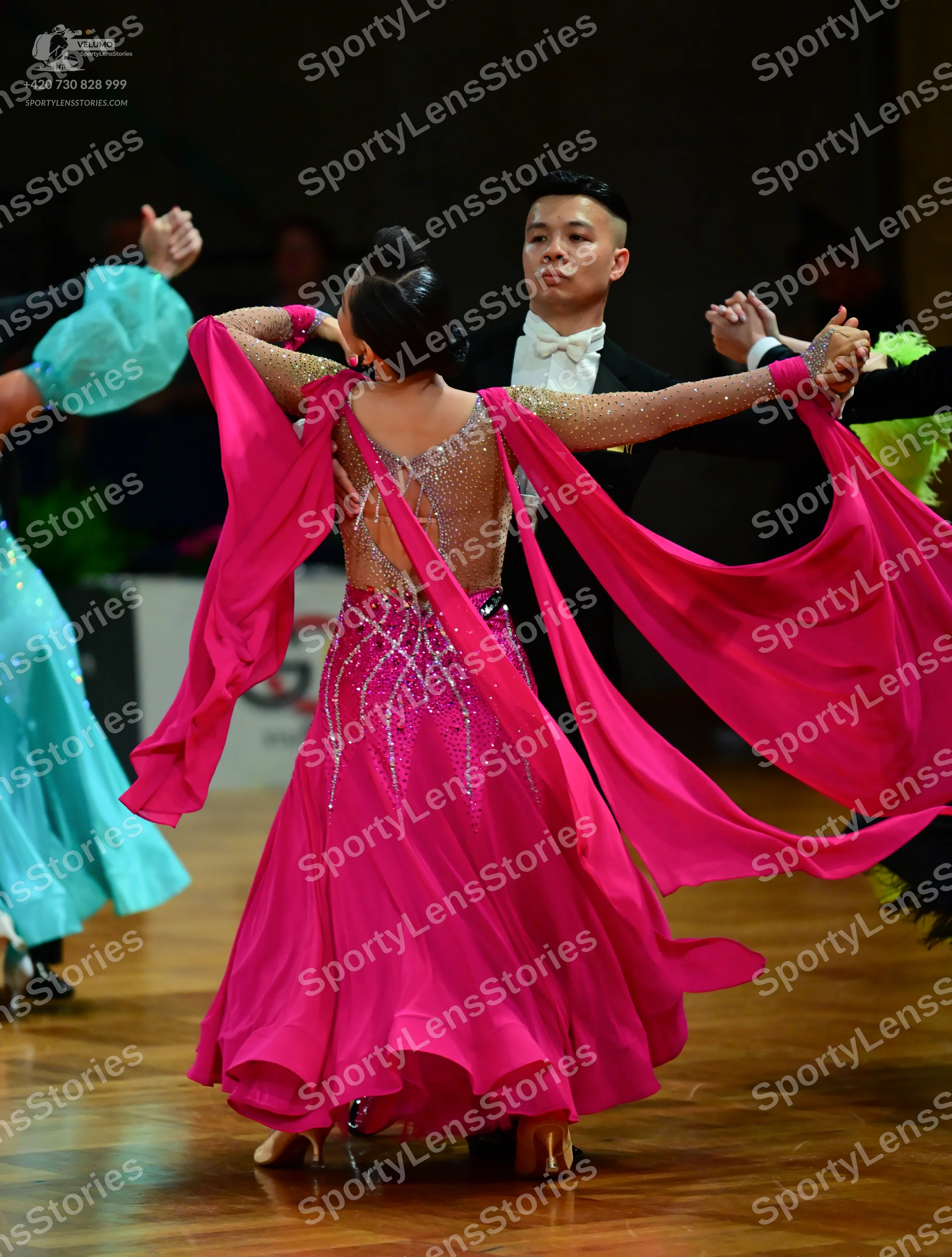 Dancesport competitor: Female dancer in foreground: magenta ballgown with a sheer, rhinestone-embellish