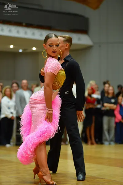 Dancesport competitor: Female dancer: bright pink Latin dance dress with gold sequin bodice and volumin