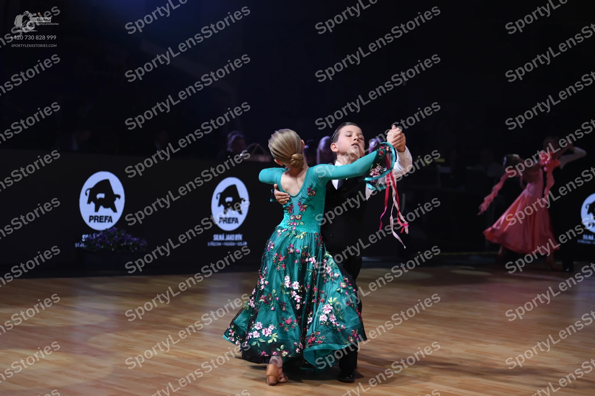 Dancesport competitor: Female dancer: teal long-sleeved ballgown with a floral pattern