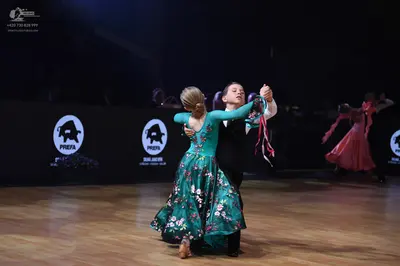 Dancesport competitor: Female dancer: teal long-sleeved ballgown with a floral pattern