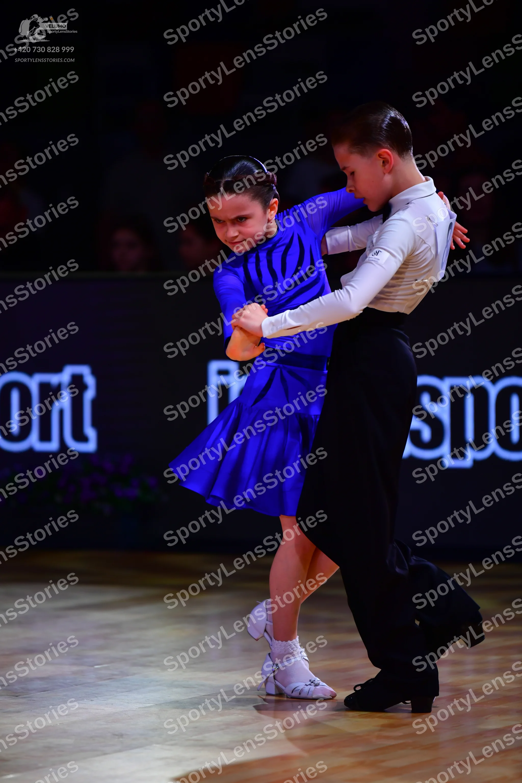 Dancesport competitor: Female dancer: royal blue short-sleeved dress made of smooth fabric and white da