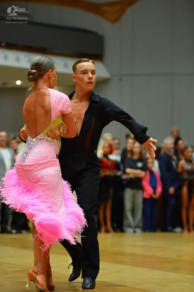 Dancesport competitor: Female dancer: pink sequined latin dress with a feathered skirt and low back