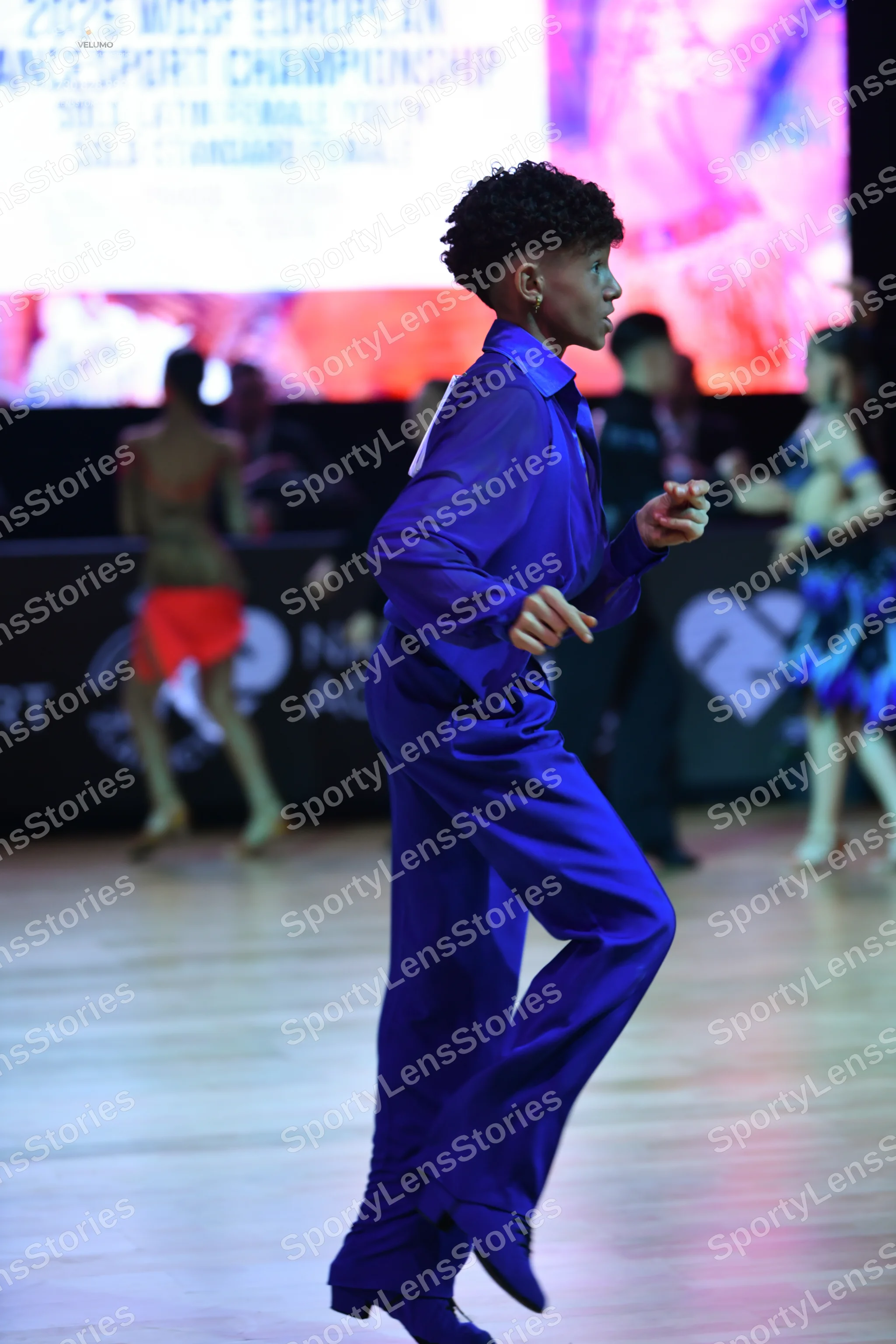 Dancesport competitor: Male dancer in foreground: blue long-sleeved shirt and matching blue trousers