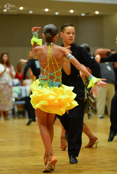 Dancesport competitor: Female dancer: yellow Latin dance costume with a multi-layered ruffled skirt and