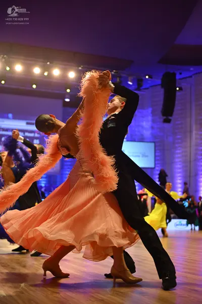 Dancesport competitor: Female dancer: peach-colored ballgown with voluminous feather trim and a flowing