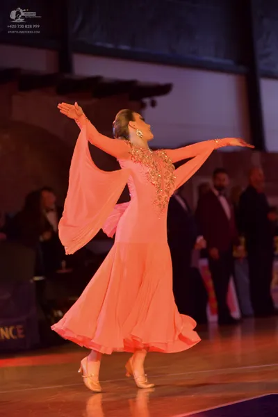 Dancesport competitor: Female dancer: peach-colored ballroom dress with a long, flowing skirt and sleev