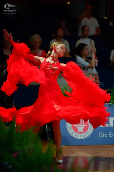 Dancesport competitor: Female dancer: red Latin dress with large, voluminous red feathered or fringed s