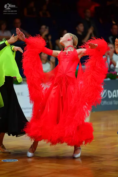 Dancesport competitor: Female dancer in center: red latin dress with large red feather trim