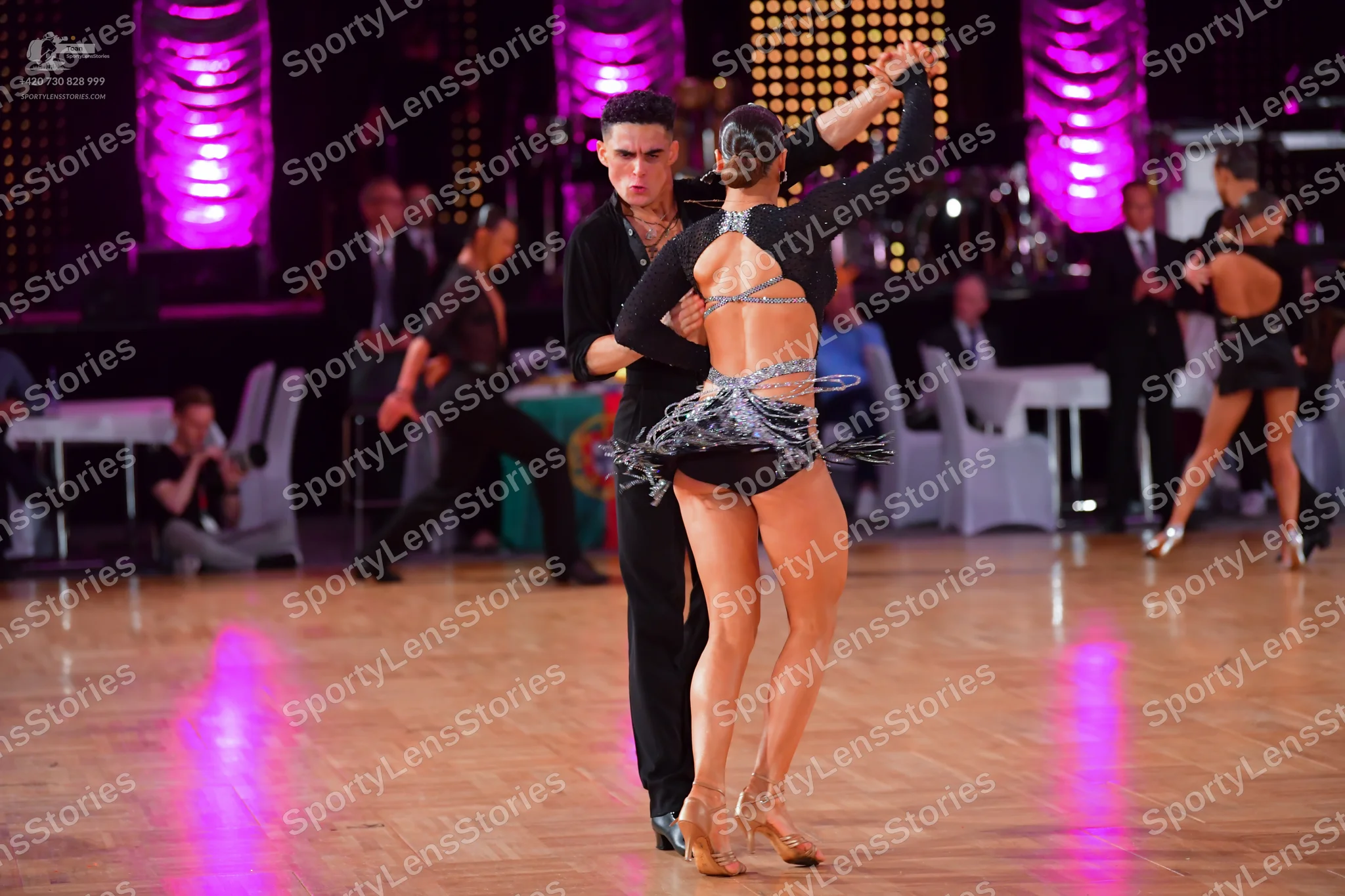 Dancesport competitor: Foreground male dancer: black long-sleeved shirt and black trousers