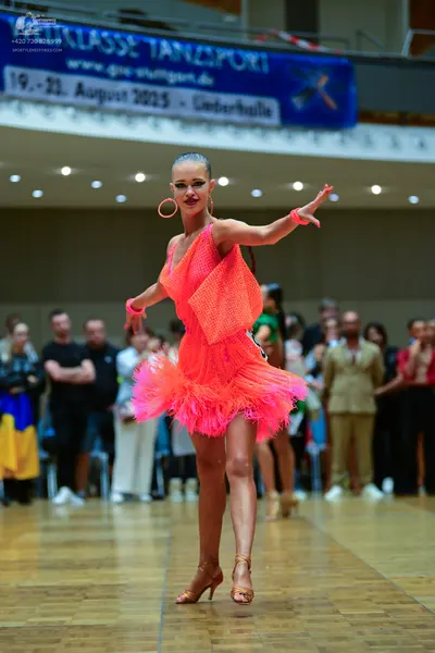 Dancesport competitor: Female dancer: neon pink Latin dress with a mesh-textured bodice and a voluminou