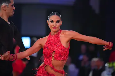 Dancesport competitor: Female dancer: red Latin dress with red sequins and lace, featuring cut-outs and
