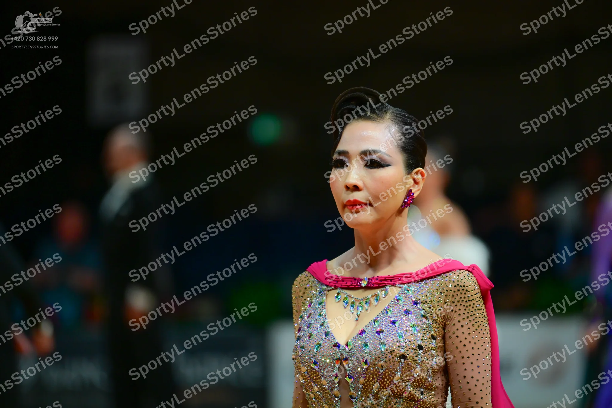 Dancesport competitor: Female dancer: nude-colored dance dress with pink/magenta fabric accents and hea
