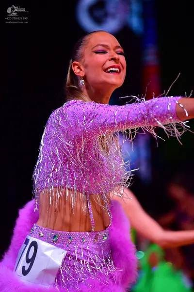 Dancesport competitor: Female dancer: pink latin dress with sequins and long fringe, featuring a furry 