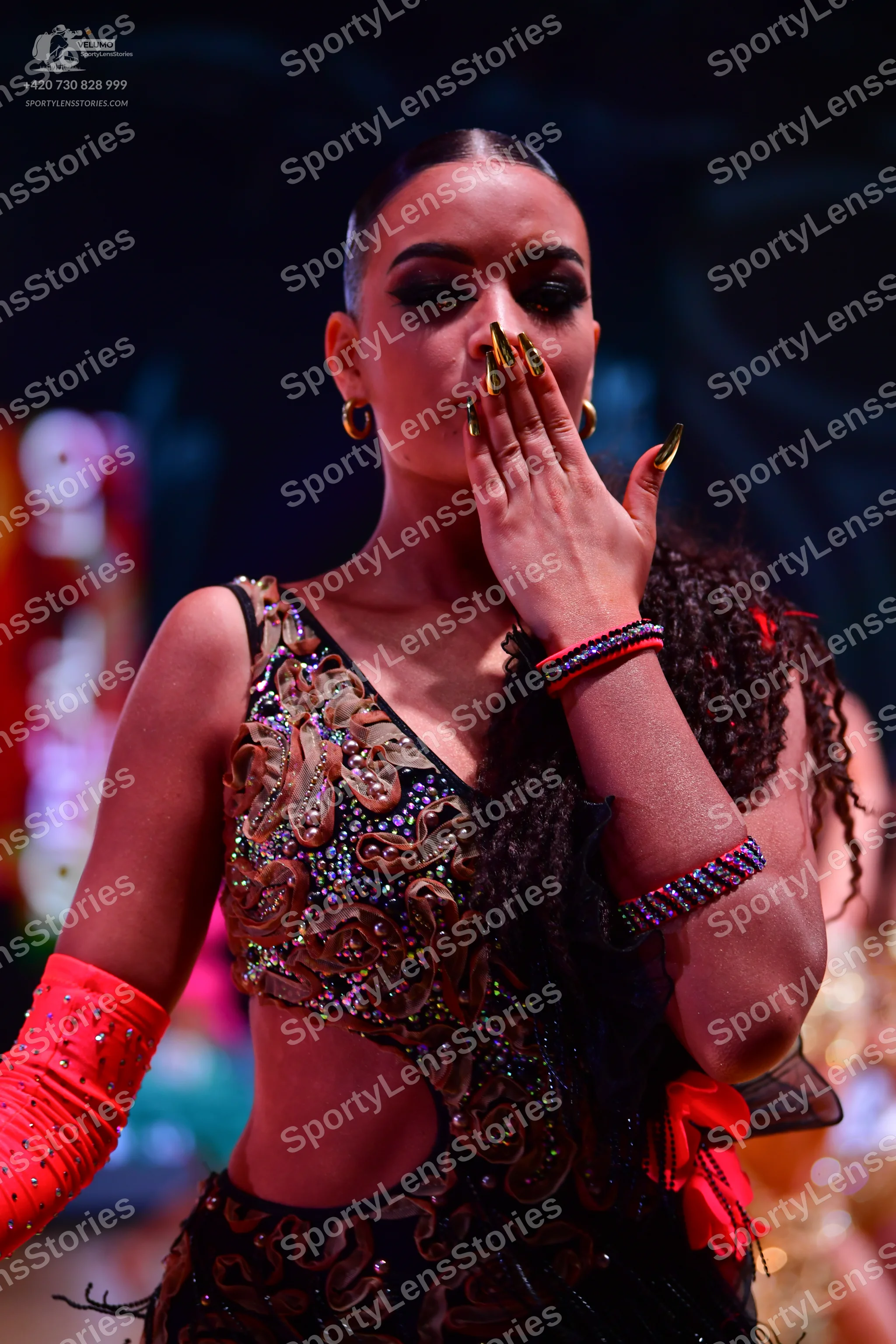Dancesport competitor: Female dancer: black latin dress with intricate gold and bronze sequin patterns,