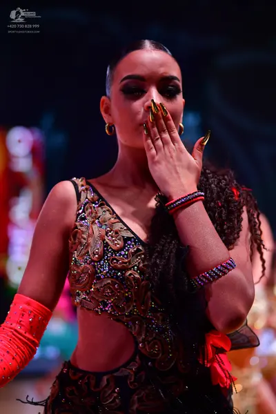 Dancesport competitor: Female dancer: black latin dress with intricate gold and bronze sequin patterns,