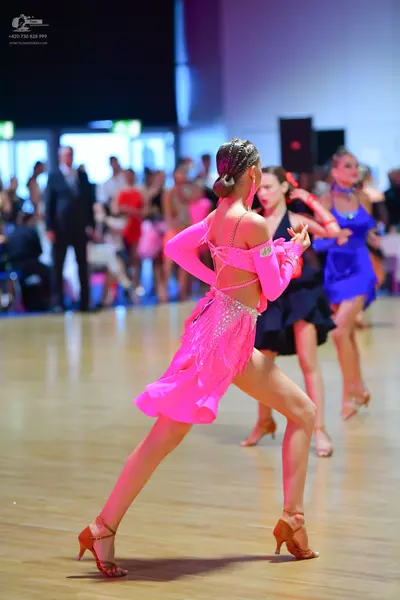 Dancesport competitor: Female dancer 1: pink latin dress with long sleeves, an open back, and sequined 