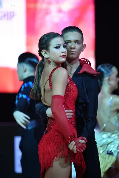 Dancesport competitor: Female dancer: red latin dress with sequins and fringe, red long gloves, and red