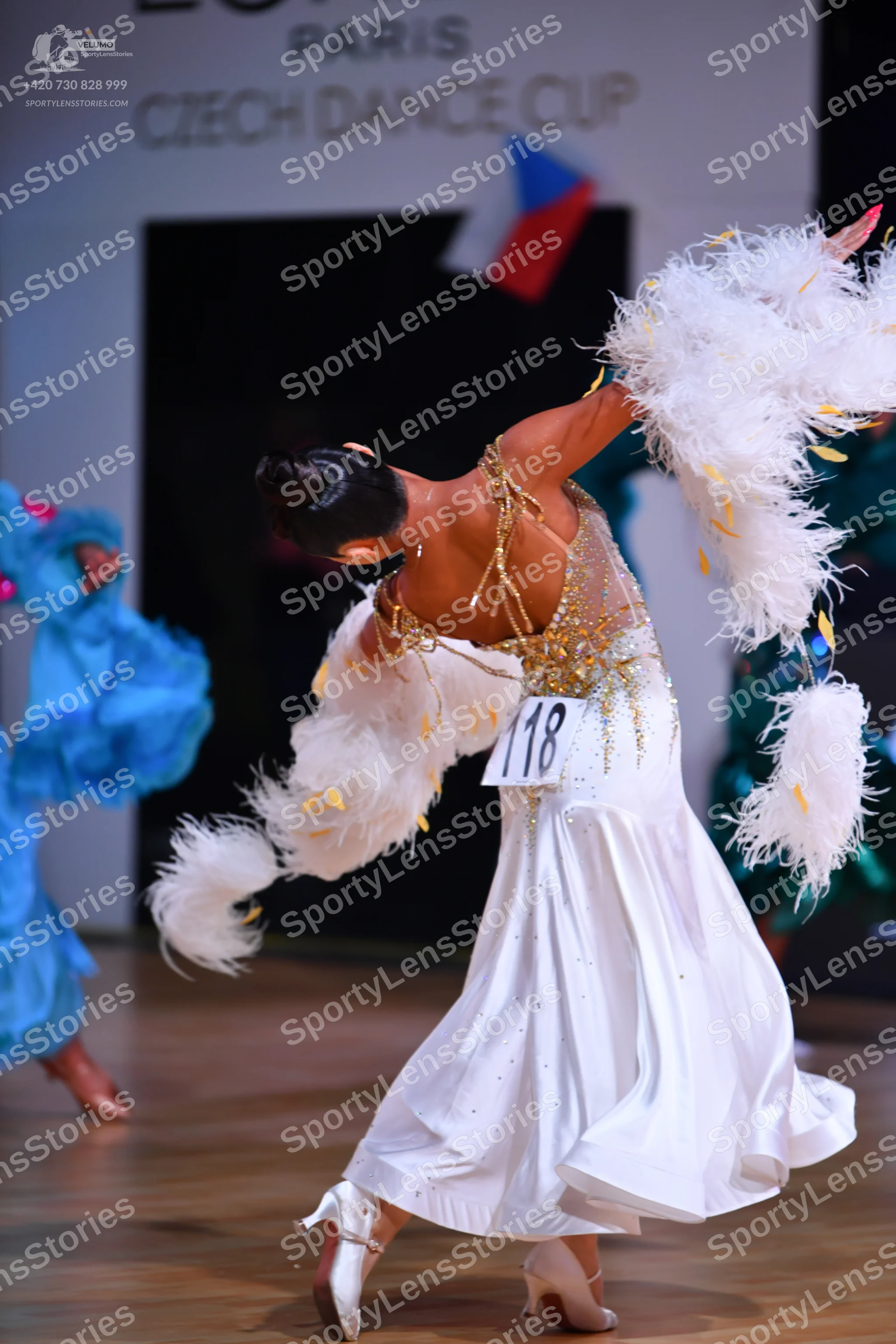 Dancesport competitor: Female dancer in foreground: white ballgown with a nude-colored bodice featuring