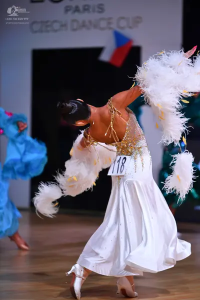 Dancesport competitor: Female dancer in foreground: white ballgown with a nude-colored bodice featuring