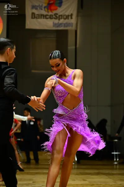 Dancesport competitor: Female dancer: purple Latin dress with sequins, cutouts, and fringe