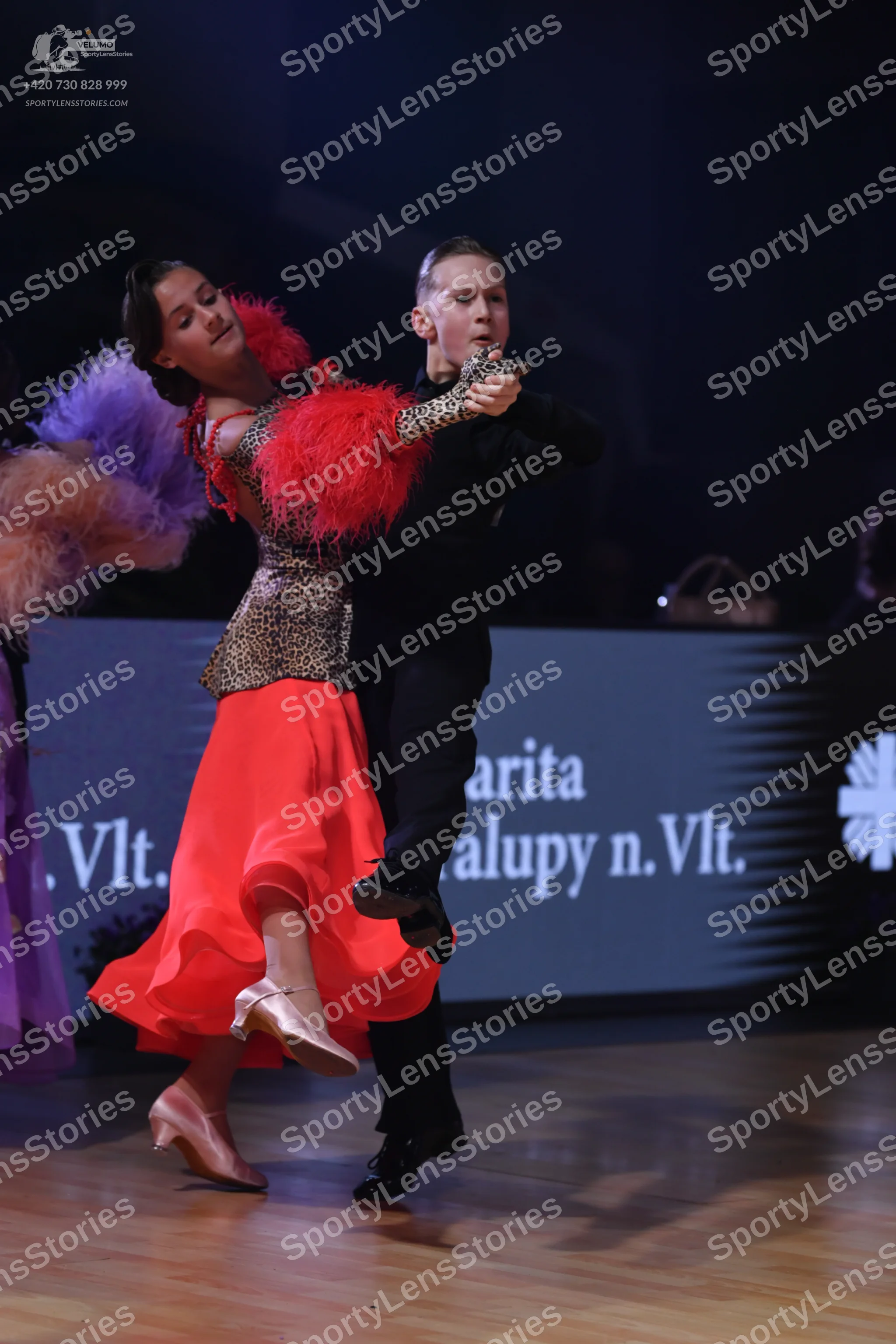 Dancesport competitor: Female dancer: leopard print bodice with large red feather trim on the shoulders