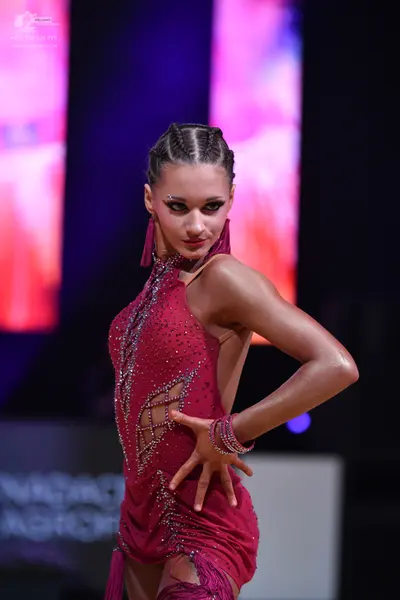 Dancesport competitor: Female dancer: burgundy latin dress with rhinestone embellishments and mesh cuto