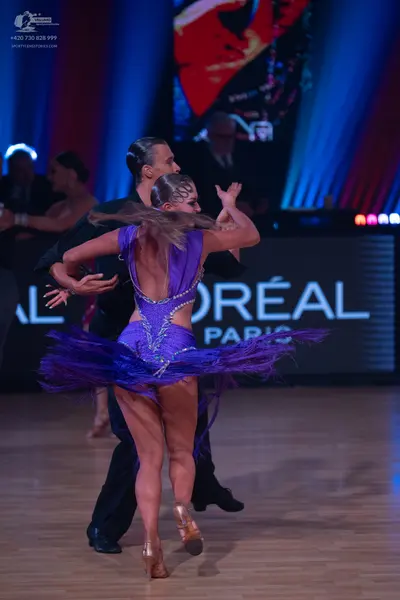 Dancesport competitor: Female dancer: purple latin dress with a sequined bodice, low back with silver r