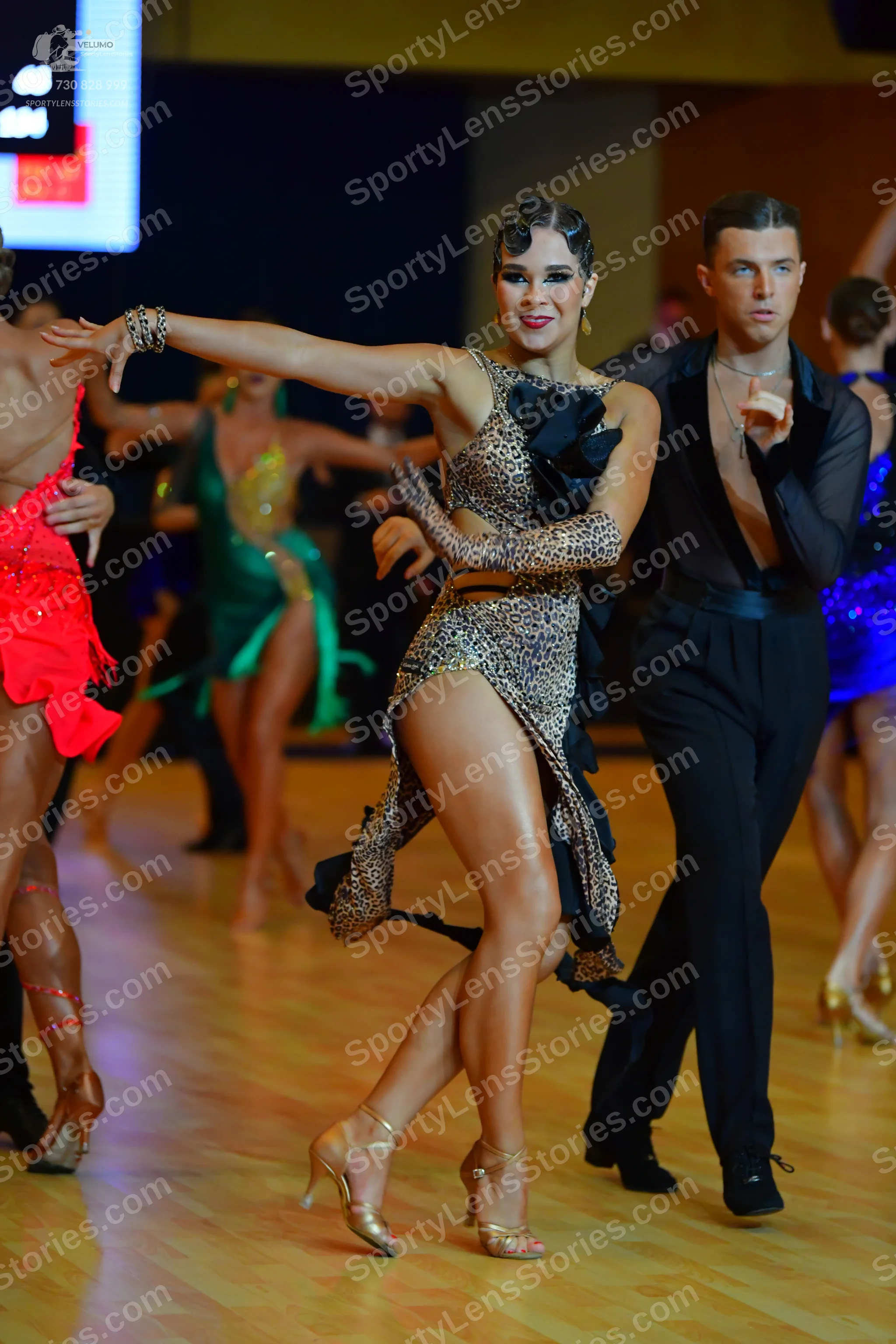 Dancesport competitor: Female dancer (center): leopard print Latin dress with a high slit and a matchin