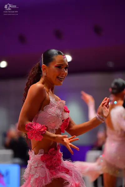 Dancesport competitor: Female dancer: pink Latin dance dress with floral lace appliqués, a skirt with p