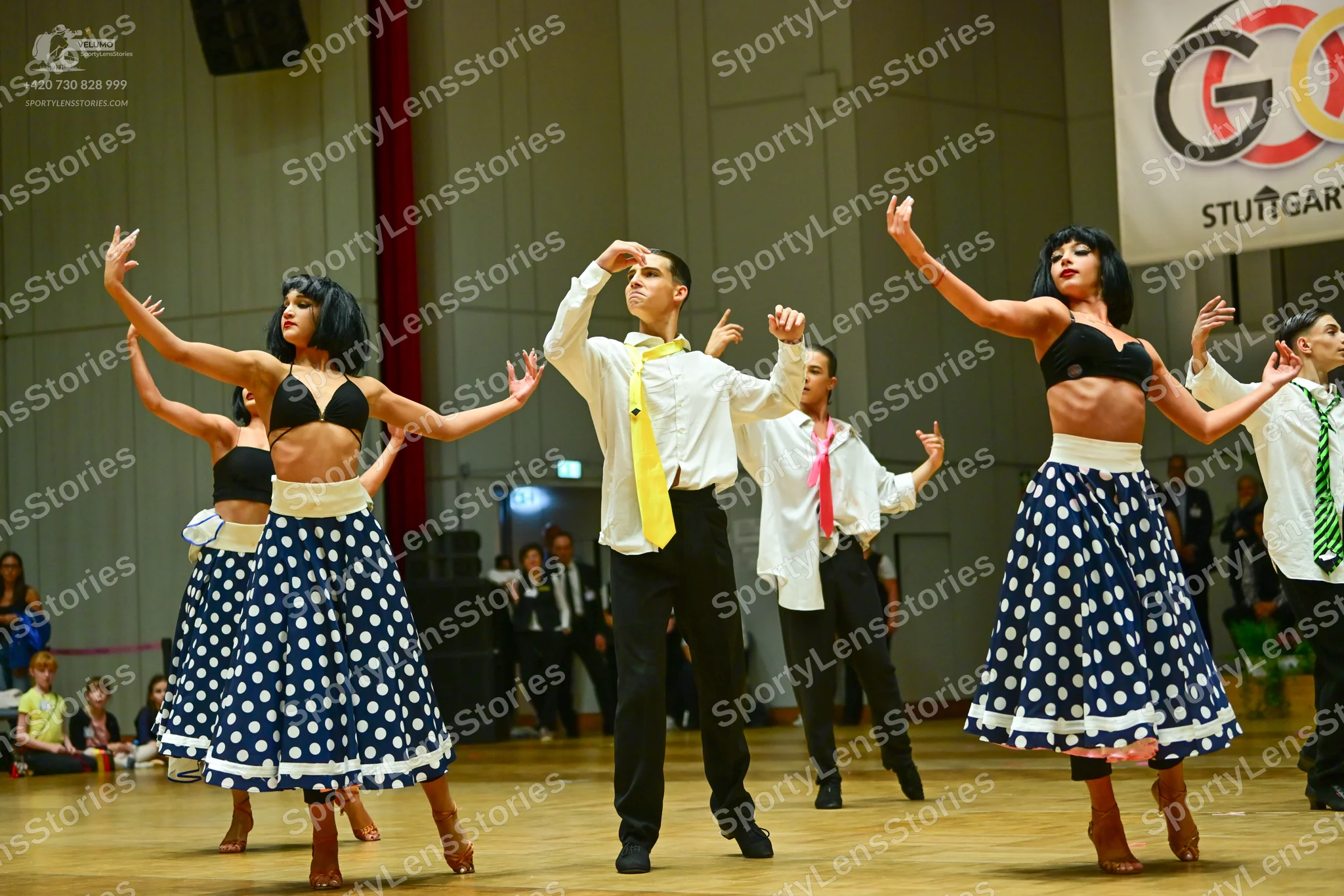 Dancesport competitor: Female dancers: black bra tops with white waistbands and dark blue skirts with w