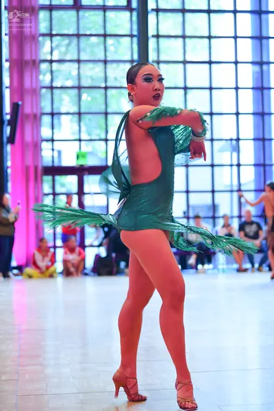 Dancesport competitor: Female dancer: emerald green latin dress with sequins and long, flowing green fr