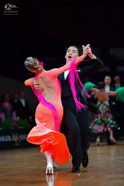 Dancesport competitor: Main female dancer: bright orange/pink Latin dance dress with long pink fringe o