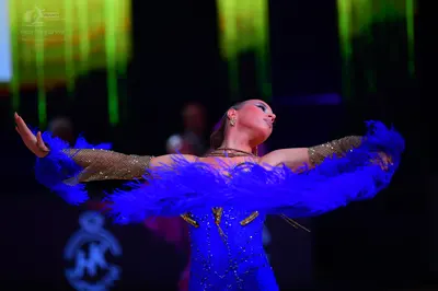 Dancesport competitor: Female dancer: blue Latin dress with blue feather accents on the sleeves and bod