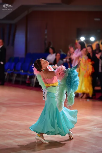 Dancesport competitor: Female dancer: light blue/aqua ballgown with pink/peach ruffled/feathered should