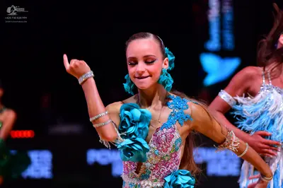 Dancesport competitor: Female dancer in center: turquoise and pink latin dress with large 3D turquoise 