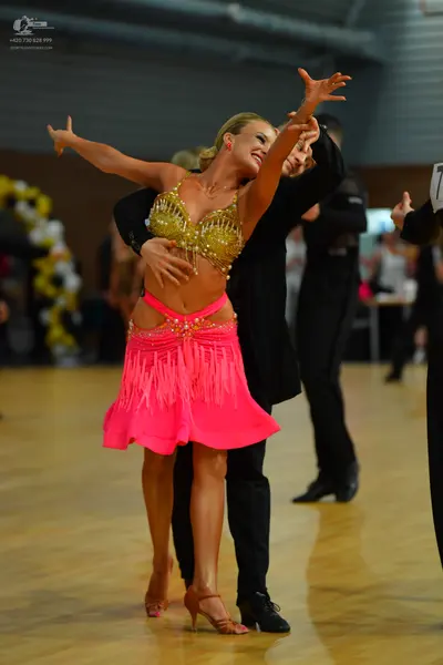 Dancesport competitor: Female dancer: gold sequined bra top and bright pink fringe skirt