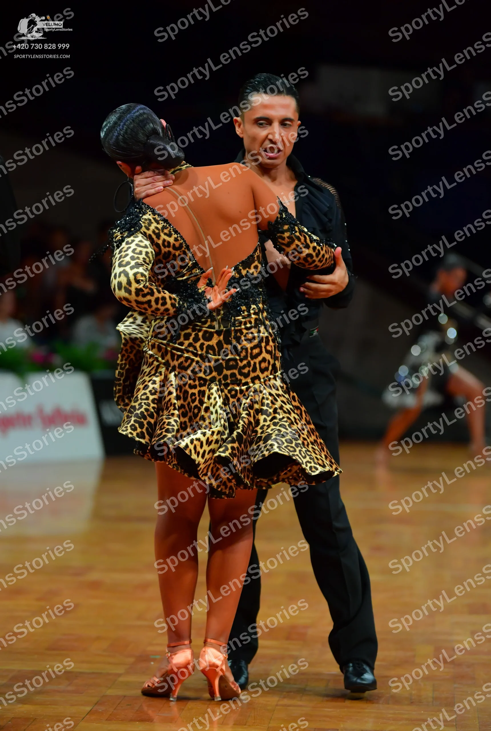 Dancesport competitor: Female dancer: leopard print Latin dress with long sleeves, a ruffled skirt, and
