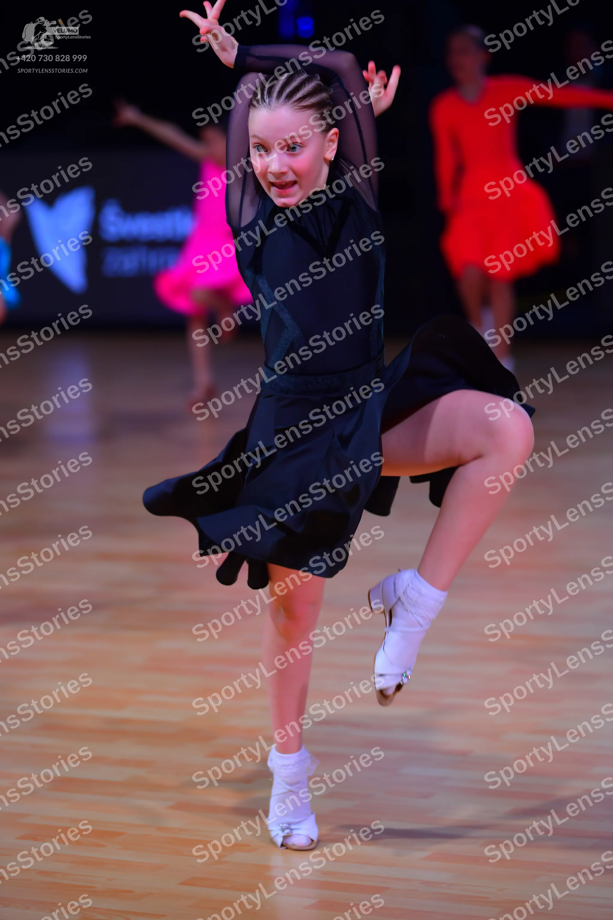 Dancesport competitor: Female dancer (foreground): black Latin dance dress with long sleeves featuring