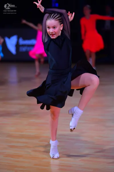 Dancesport competitor: Female dancer (foreground): black Latin dance dress with long sleeves featuring 