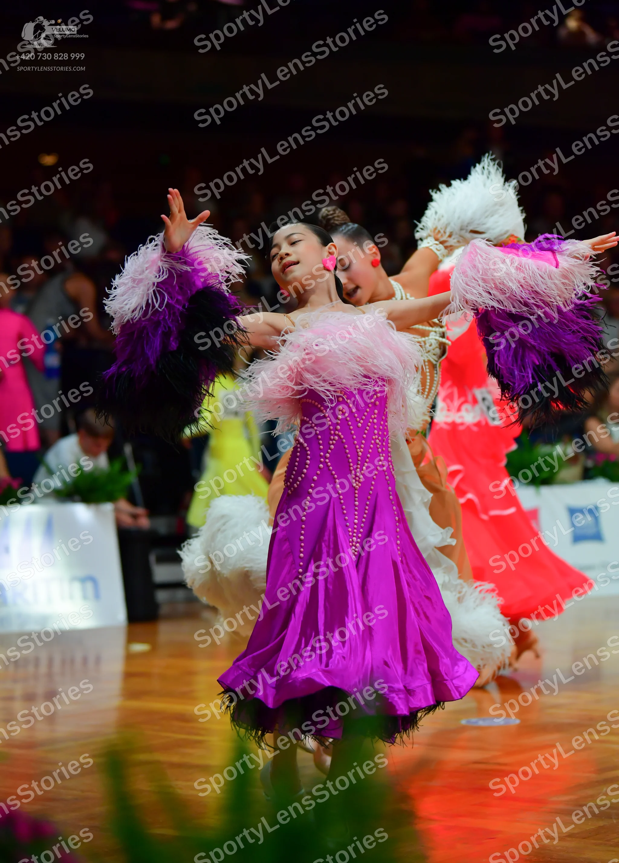 Dancesport competitor: Female dancer 1: purple satin Latin dress with large white, pink, and dark purpl