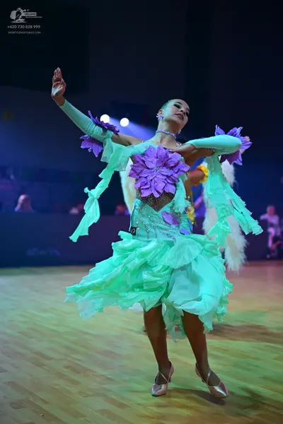 Dancesport competitor: Female dancer: mint green Latin dress with large purple fabric flowers, ruffles,