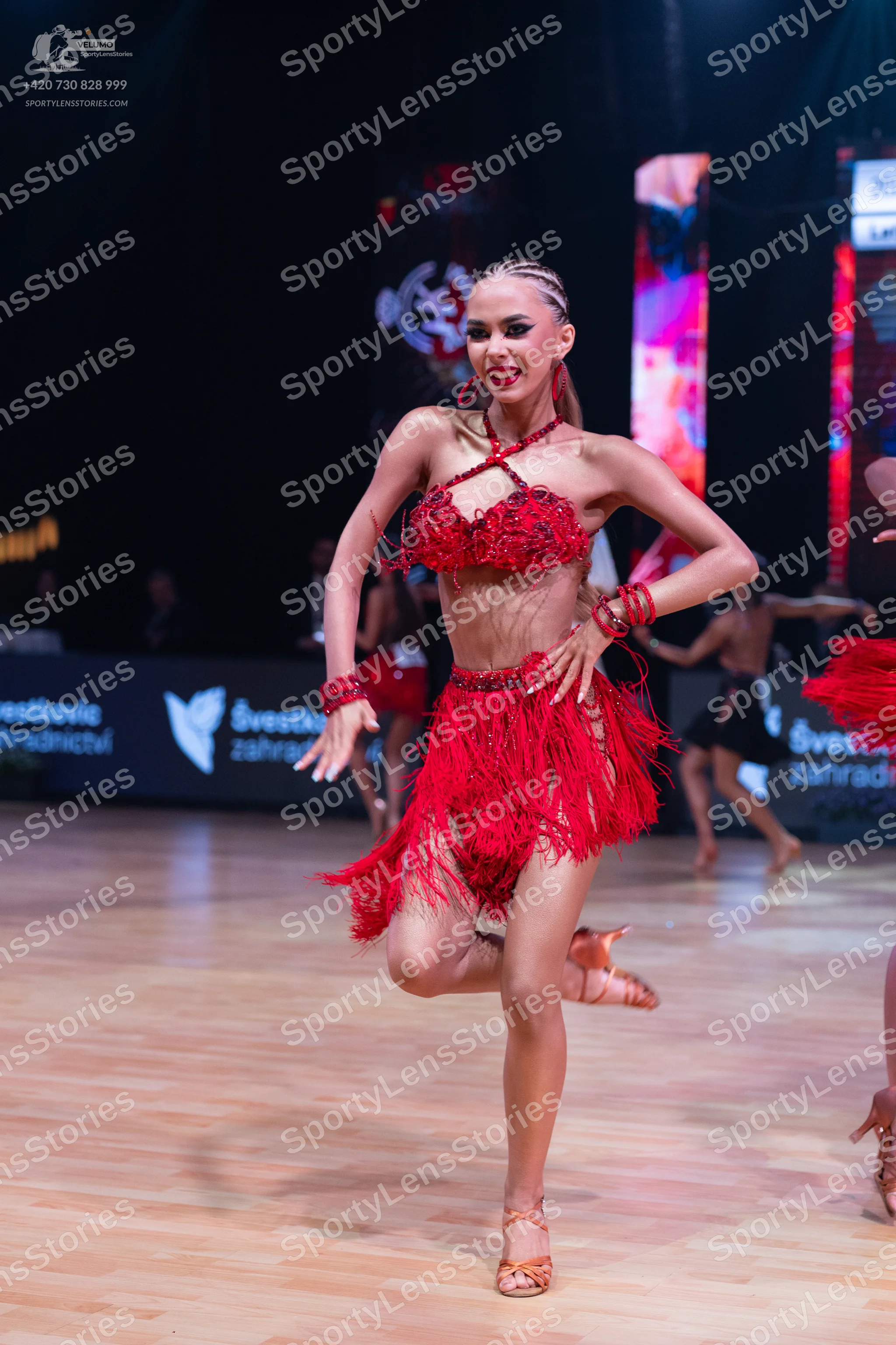 Dancesport competitor: Main female dancer: red Latin costume featuring a sequined halter top and a shor