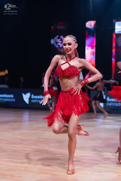 Dancesport competitor: Main female dancer: red Latin costume featuring a sequined halter top and a shor