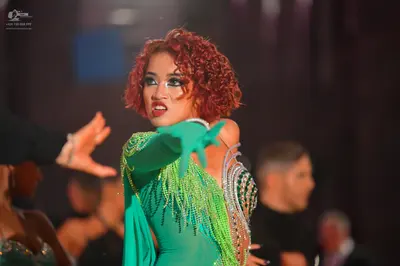 Dancesport competitor: Female dancer: green Latin dance dress with silver sequins and long green fringe