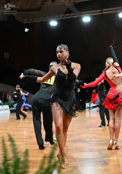 Dancesport competitor #71: Female dancer in center: black latin dress with sequins and fringe, black long g