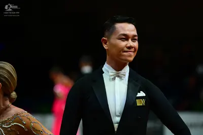 Dancesport competitor: Male dancer: black tuxedo with a white shirt, white bow tie, and white pocket sq